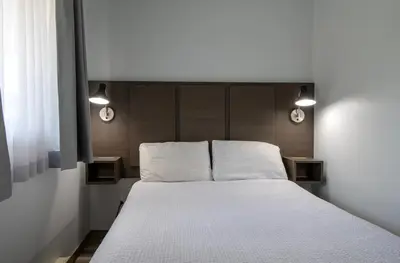 a bedroom with a bed with two lights on it at Riverland Inn & Suites in Kamloops