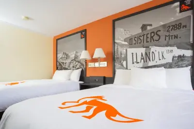 two beds in a hotel room with orange walls at Fernie Fox Hotel in Fernie
