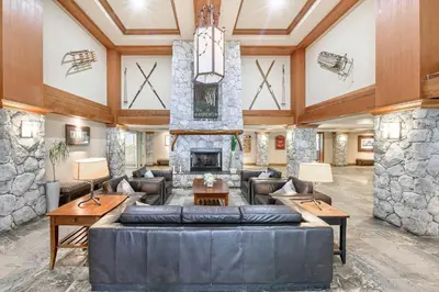a living room with a large couch and a stone fireplace at The Best Top Floor Ski-in/Ski-out at the Aspens in Whistler