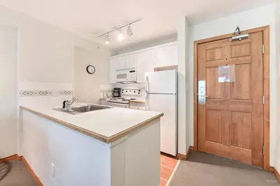 a white kitchen with a sink and a refrigerator at The Best Top Floor Ski-in/Ski-out at the Aspens in Whistler