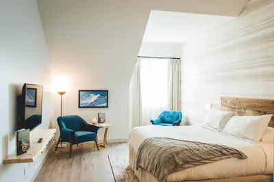 a bedroom with a bed and two blue chairs at Glacier View Lodge in Sunwapta