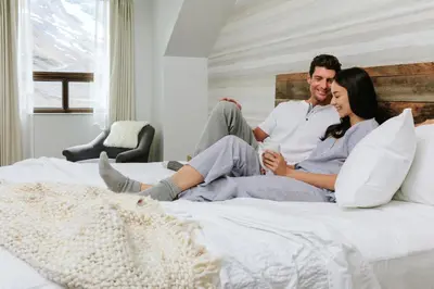 a man and woman sitting on a bed at Glacier View Lodge in Sunwapta