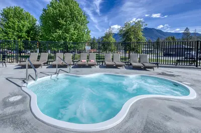 a hot tub with chairs and a fence at Bighorn Meadows Resort in Radium Hot Springs