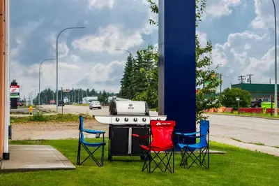 a grill with three chairs around it on the grass at Comfort Inn & Suites in Edson