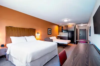 a hotel room with a large bed and a kitchen at Four Points by Sheraton Grande Prairie in Grande Prairie