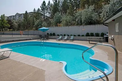 a large swimming pool with chairs and an umbrella at Travelodge by Wyndham Kamloops Mountview in Kamloops