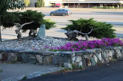 a garden with purple flowers in a stone wall at Best Budget Inn & Suites Kamloops in Kamloops