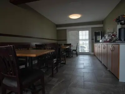 a dining room with tables and chairs and a kitchen at Best Budget Inn & Suites Kamloops in Kamloops