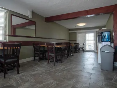 a dining room with a table and chairs and a refrigerator at Best Budget Inn & Suites Kamloops in Kamloops