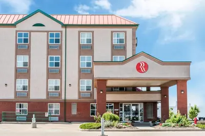 a large brick building with a red roof at Ramada by Wyndham Sherwood Park in Sherwood Park