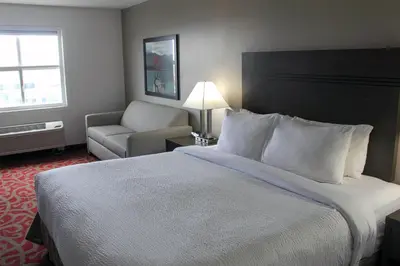 a hotel room with a large bed and a chair at Ramada by Wyndham Sherwood Park in Sherwood Park
