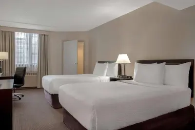 a hotel room with two beds and a desk at Ramada Plaza by Wyndham Calgary Downtown in Calgary