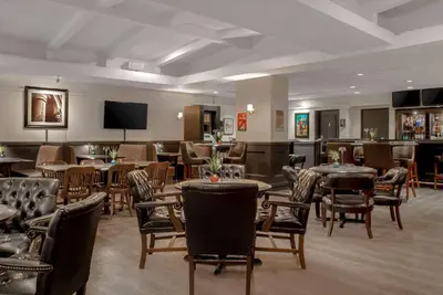 a restaurant with tables and chairs and a flat screen tv at Ramada Plaza by Wyndham Calgary Downtown in Calgary