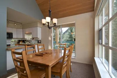 a kitchen and dining room with a wooden table and chairs at Snowbird by Bill in Whistler