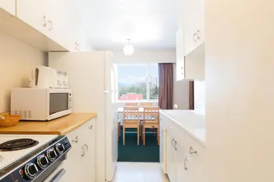 a kitchen with white cabinets and a microwave and a table at English Bay Hotel in Vancouver