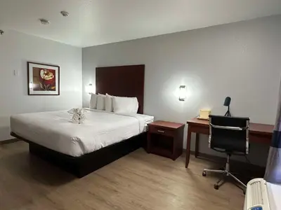 a hotel room with a bed and a desk and a chair at SureStay Plus by Best Western Brooks in Brooks
