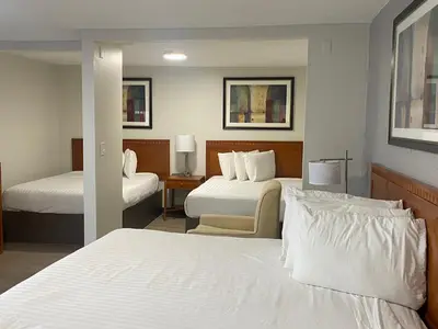 a hotel room with two beds and a chair at Riverside Motel in Penticton