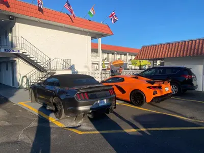 two cars parked in a parking lot next to a building at Riverside Motel in Penticton