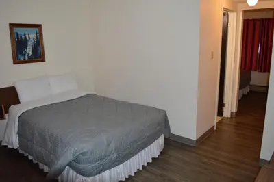 a bedroom with a bed in a white room at A1 Motel And Campground in Bassano