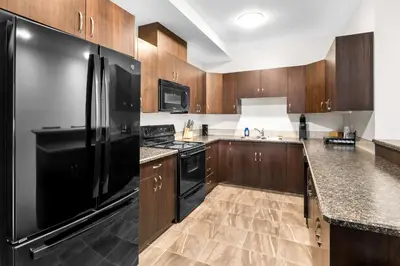 a kitchen with a black refrigerator and wooden cabinets at SureStay Studio by Best Western Hardisty in Hardisty