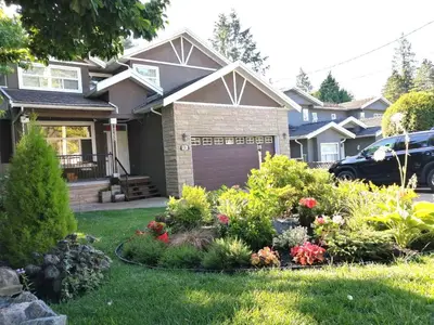 a house with a garden of flowers in the yard at Three Kittens Guesthouse in Burnaby
