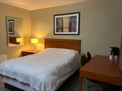 a bedroom with a bed and a table with a lamp at Schell Motel in Vernon