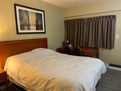 a bedroom with a bed and a desk and a window at Schell Motel in Vernon
