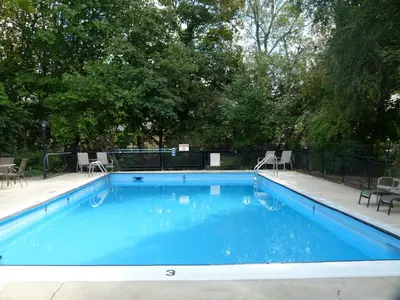 a large blue swimming pool with chairs and trees at Schell Motel in Vernon