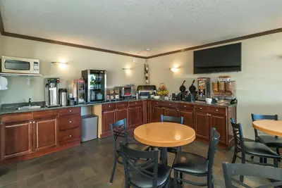 a kitchen with wooden cabinets and a table and chairs at Quality Inn & Suites in Vernon