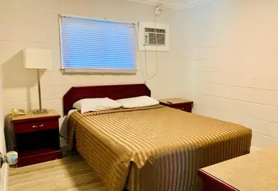a small bedroom with a bed and a window at Traveler's Motel Penticton in Penticton