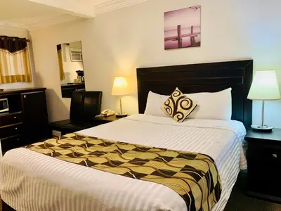 a hotel room with a large bed and two lamps at Traveler's Motel Penticton in Penticton