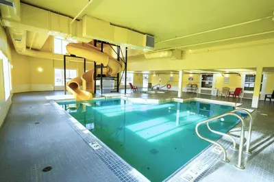 a large swimming pool with a slide in a building at Ramada by Wyndham Cranbrook in Cranbrook