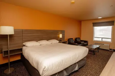 a hotel room with a large bed and a chair at Ramada by Wyndham Cranbrook in Cranbrook
