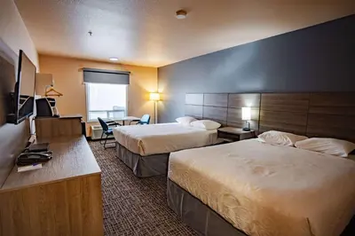 a hotel room with two beds and a desk at Ramada by Wyndham Cranbrook in Cranbrook