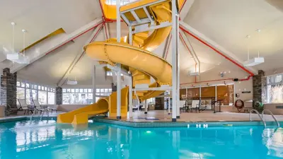a swimming pool with a yellow slide in a building at Pocaterra Inn & Waterslide in Canmore
