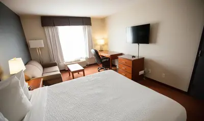 a hotel room with a bedroom with a bed and a desk at Super 8 by Wyndham Whitecourt in Whitecourt