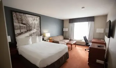 a hotel room with a large bed and a couch at Super 8 by Wyndham Whitecourt in Whitecourt