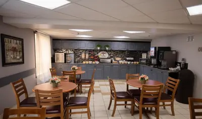 a restaurant with tables and chairs and a kitchen at Super 8 by Wyndham Whitecourt in Whitecourt