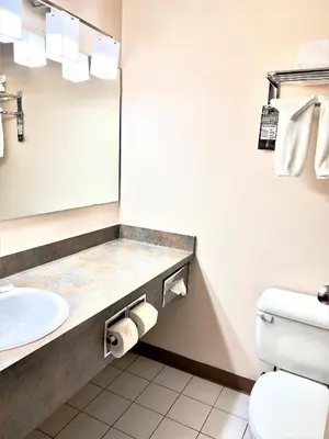 a bathroom with a sink and a toilet and a mirror at Super 8 by Wyndham Whitecourt in Whitecourt