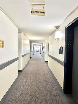a hallway of an office building with a sign that reads elevator at Super 8 by Wyndham Whitecourt in Whitecourt