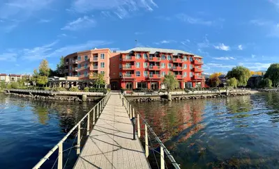 a red building on a bridge over a river at Manteo at Eldorado Resort in Kelowna