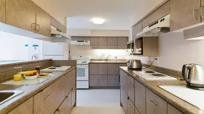 a large kitchen with wooden cabinets and white appliances at Hotel Willo - previously known YWCA Hotel in Vancouver