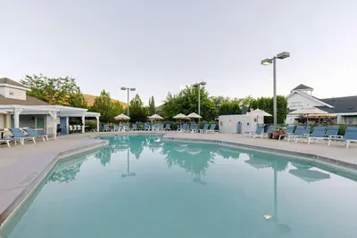 a large swimming pool with chairs and umbrellas at Balcomo, a Ramada by Wyndham in Penticton