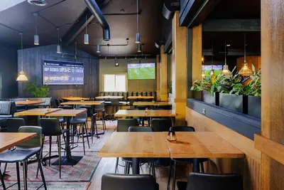 a restaurant with wooden tables and chairs and plants at Balcomo, a Ramada by Wyndham in Penticton