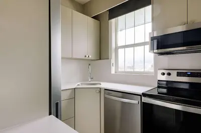 a kitchen with white cabinets and a sink and a window at Balcomo, a Ramada by Wyndham in Penticton