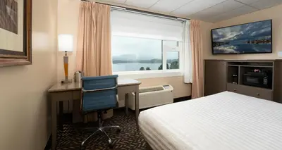 a hotel room with a bed and a desk and a window at Prestige Oceanview Hotel Prince Rupert in Prince Rupert
