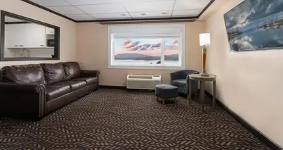 a living room with a leather couch and a window at Prestige Oceanview Hotel Prince Rupert in Prince Rupert
