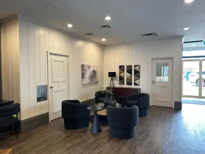 a lobby with blue chairs and a table and a room at Prestige Oceanview Hotel Prince Rupert in Prince Rupert