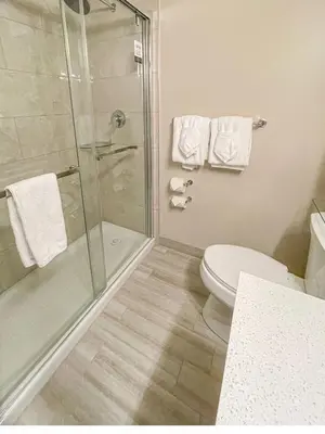 a bathroom with a toilet and a shower with towels at Prestige Oceanview Hotel Prince Rupert in Prince Rupert