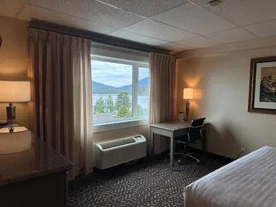 a hotel room with a bed and a desk and a window at Prestige Oceanview Hotel Prince Rupert in Prince Rupert